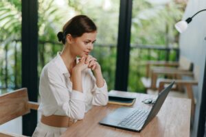 Smiling Freelancer Working on Laptop at Home Office A cheerful young woman with a laptop sits at her