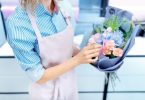 cropped shot of florist arranging bouquet of flowers in flower shop