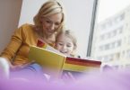 Mother reading picture book to daughter